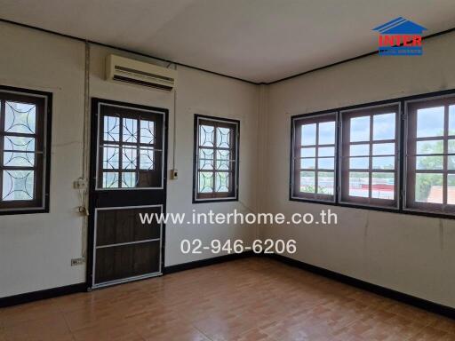 A room with windows, an air conditioner, and a door.