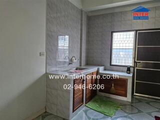 Modern kitchen with tiled walls, sink, cabinets, and window