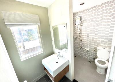 Modern bathroom with sink, mirror, window, and shower area