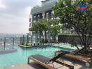 View of an outdoor pool area with lounge chairs and a modern building in the background