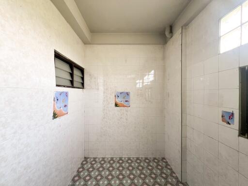 White-tiled bathroom with windows and decorative wall tiles