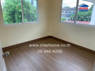 Empty bedroom with wooden flooring and large windows