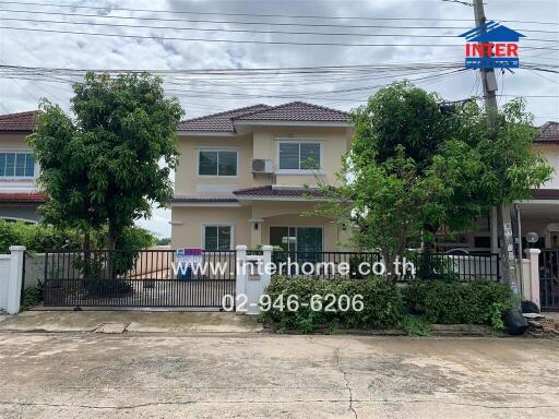 Two-story house exterior with driveway and surrounding greenery