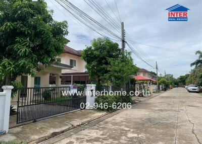 Street view of houses and gated property with trees