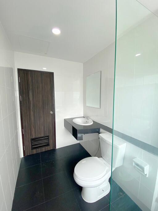 Modern bathroom with glass partition and dark floor tiles