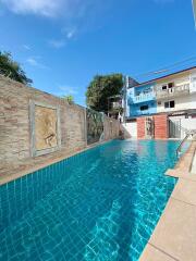 A private swimming pool with decorative wall art and surrounding buildings.