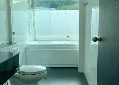 Modern bathroom with glass shower, bathtub, and large window
