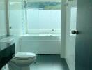 Modern bathroom with glass shower, bathtub, and large window