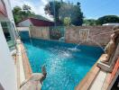 Outdoor swimming pool with decorative statues and artwork on the wall