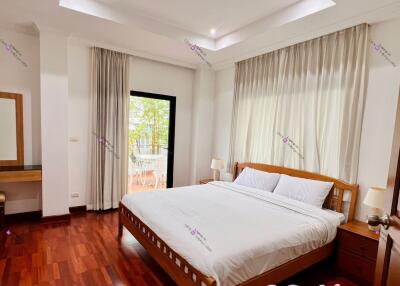 Spacious bedroom with a double bed, large windows, and wooden flooring