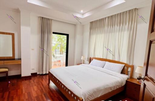 Spacious bedroom with a double bed, large windows, and wooden flooring