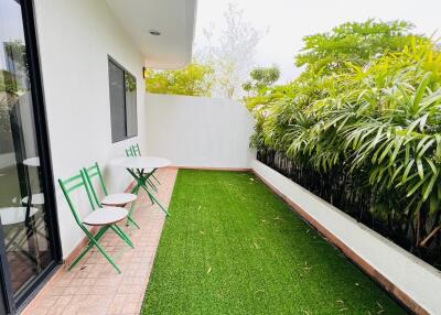 Outdoor patio with green artificial grass, small round tables, and chairs
