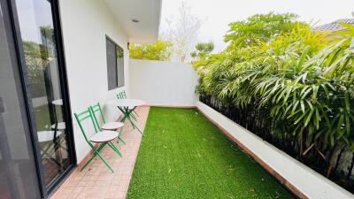 Outdoor patio with green artificial grass, small round tables, and chairs