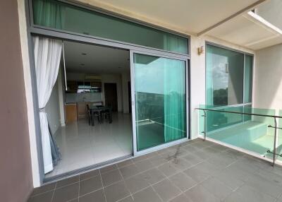Spacious balcony with sliding glass doors and a view of the kitchen and living area
