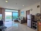 Modern living room with ocean view, including dining area, sofa, glass table, and kitchenette.