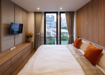 Modern bedroom with city view, wall-mounted TV, and wooden furniture
