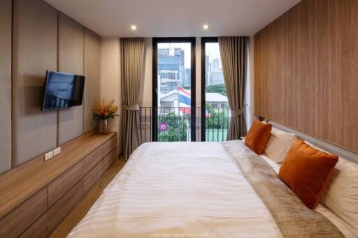 Modern bedroom with city view, wall-mounted TV, and wooden furniture