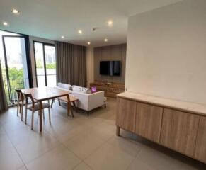 Modern living room with a dining set, sofa, TV, and balcony.