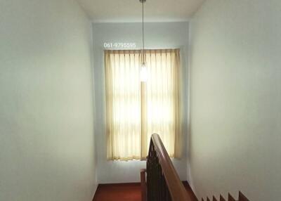 Staircase leading to upper floor with hanging light fixture and window with curtains
