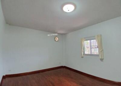 Empty bedroom with hardwood floors and window with curtains