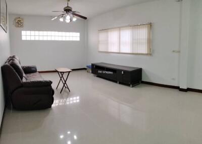 Spacious living room with sofa, coffee table, ceiling fan, and large windows