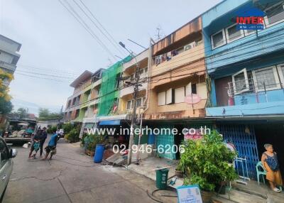 Street view of colorful residential buildings with people and plants.