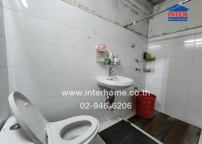 A bathroom with a toilet, sink, and red bucket