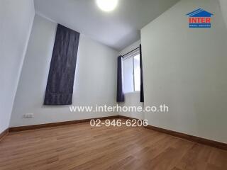 Unfurnished bedroom with large window and wooden floor