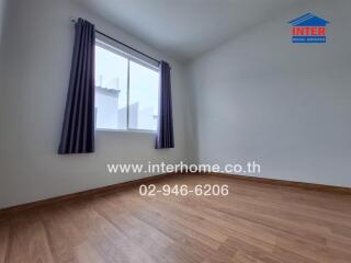 Empty bedroom with wooden floor and a window curtain