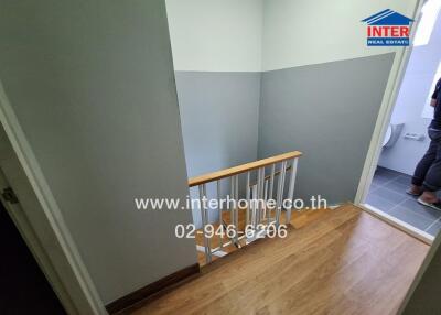 Stairwell with wooden flooring and grey walls in a property