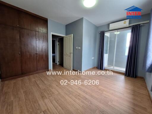 Spacious bedroom with hardwood flooring and built-in wooden wardrobe