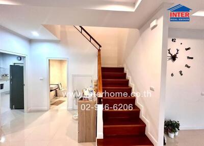 Hallway with stairs leading to upper floor, entry to kitchen and dining room visible