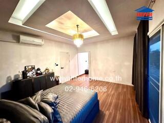 Spacious master bedroom with wooden floors, large windows, and ceiling lighting.