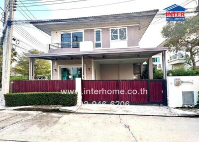 Two-story modern house with a red gate and surrounding greenery