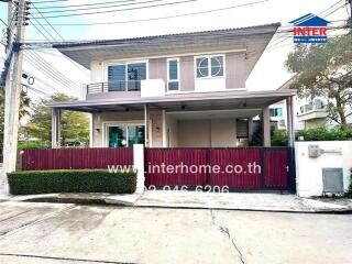 Two-story modern house with a red gate and surrounding greenery