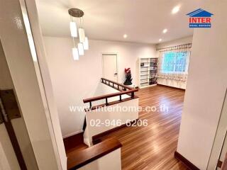 Spacious and well-lit living area with wooden flooring and modern lighting