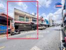 Street view of commercial building with busy road and shops