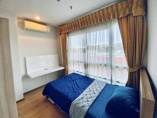 A modern bedroom with a neatly made bed and large window with curtains