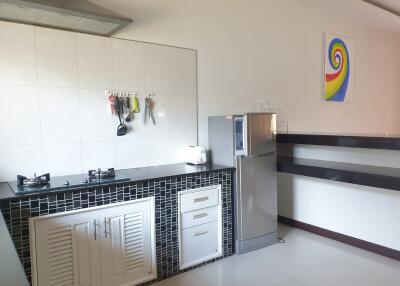 Modern kitchen with dual burner stove, overhead hood, refrigerator, and colorful wall art