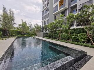 View of an outdoor swimming pool with adjacent modern apartment building