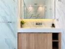 Modern bathroom with a large mirror, wooden cabinet, and marble walls