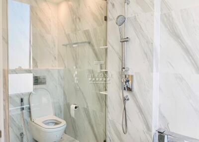 Modern bathroom with marble tiles, toilet, and shower