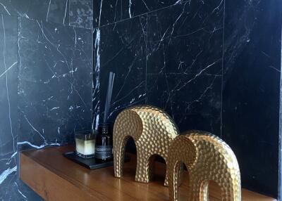 Marble tiled surface with decorative golden elephant sculptures and wooden ledge
