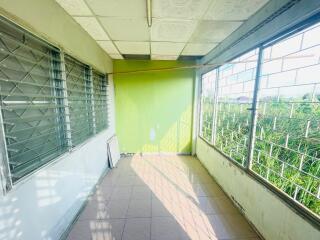 Bright enclosed balcony with tiled floor and large windows