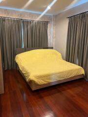 Bedroom with wooden flooring and curtains