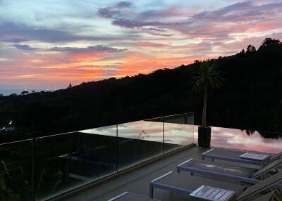 Sunset view from patio with lounge chairs and glass railing