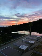 Sunset view from patio with lounge chairs and glass railing