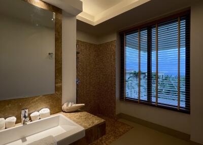Modern bathroom with vanity, a large mirror, and a view through blinds.
