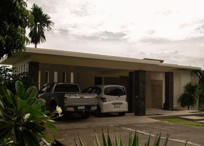 Front view of a modern house with covered driveway and parked cars