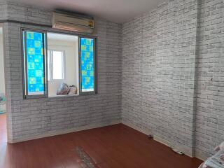 Unfurnished bedroom with brick-patterned wallpaper and wooden flooring